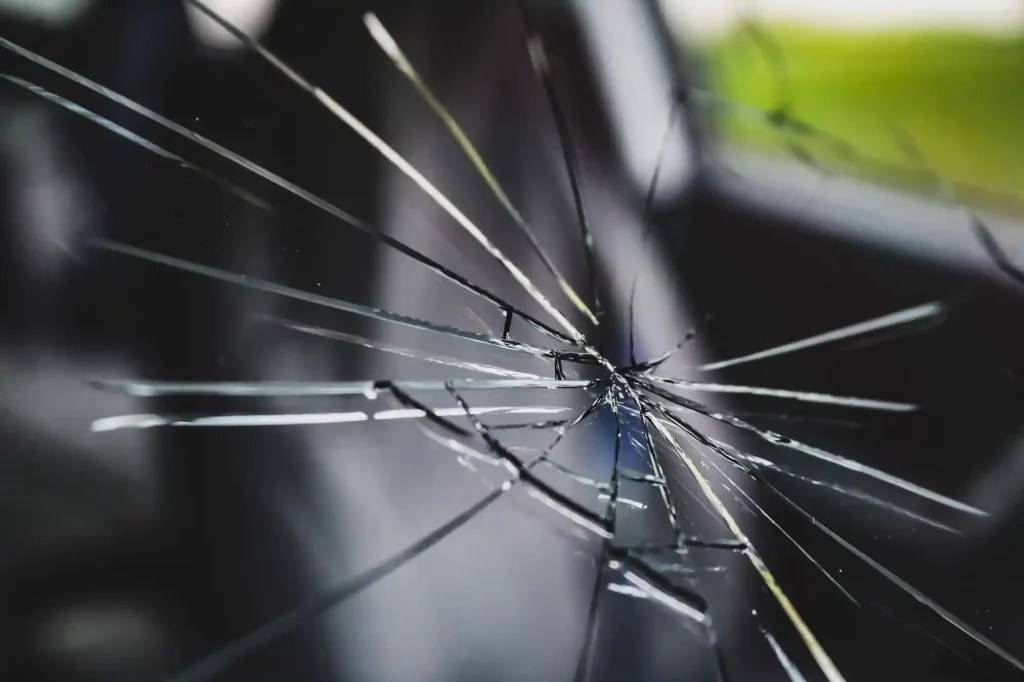 regarder un morceau de verre brisé sur un pare-brise de voiture avec un point d'impact central et des fissures radiales. élément de conception automobile et de transport.